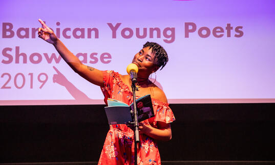 Image of previous young poets showcase. Black woman performing on stage.