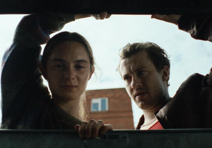 A girl and a man look into a boot of a car.
