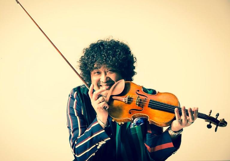 Taro Hakase holding his violin and smiling at the camera