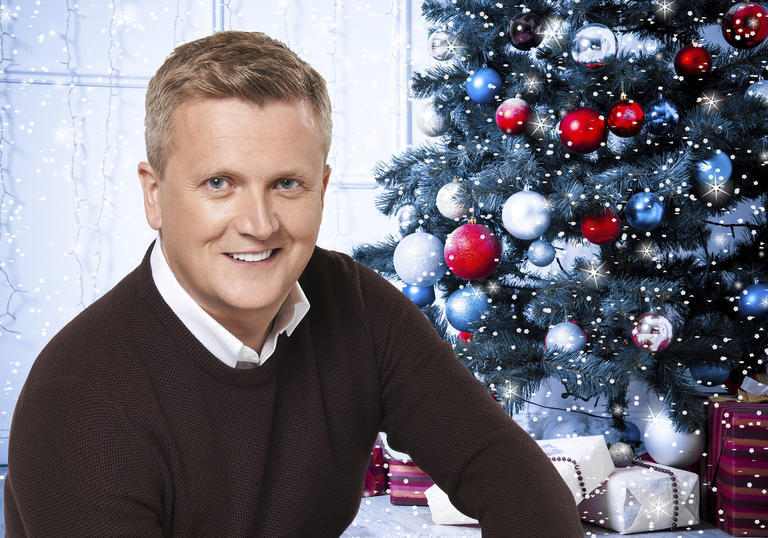 Aled Jones smiling in front of a Christmas tree