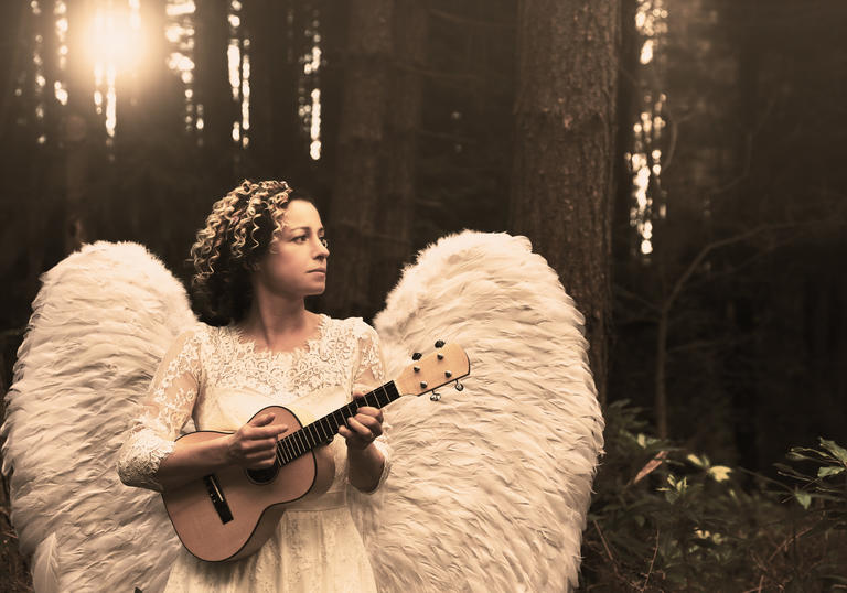 Kate Rusby dressed as an angel holding a ukelele and staring into the distance