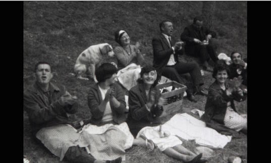 a black and white image of a group of people having a picnic