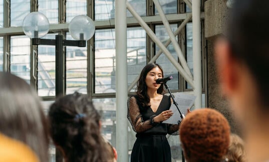 performer wearing a black dress standing in front of a microphone inside the conservatory