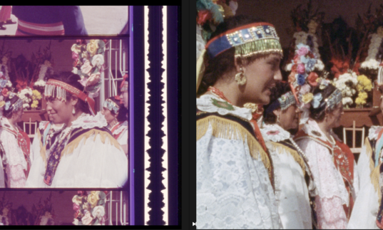 A 35mm film still of a group of women dressed up for ceremony in white clothes and headdresses.