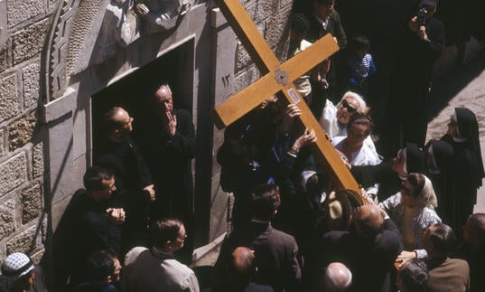 Photo of large cross being carried during performance of St John Passion