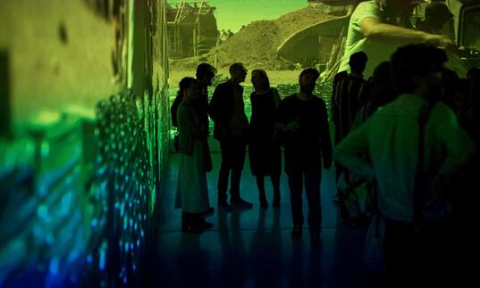 Photo of young people in a gallery by large film projections