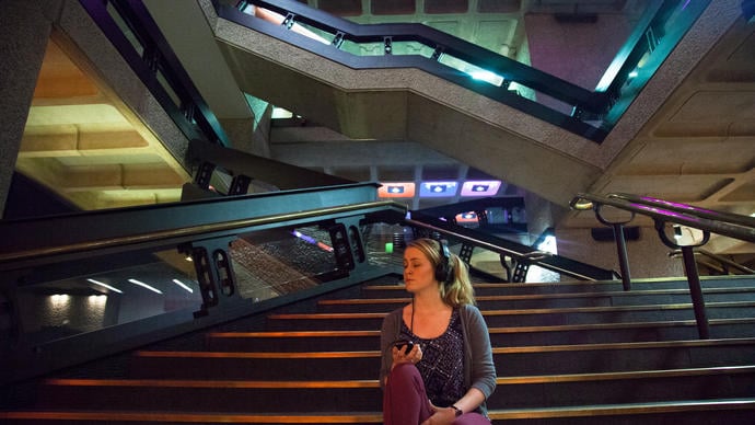 Photo of woman sitting on stairs listening to headphones