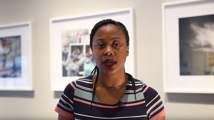 photo of young reviewer barbara ojei standing in front of photographs