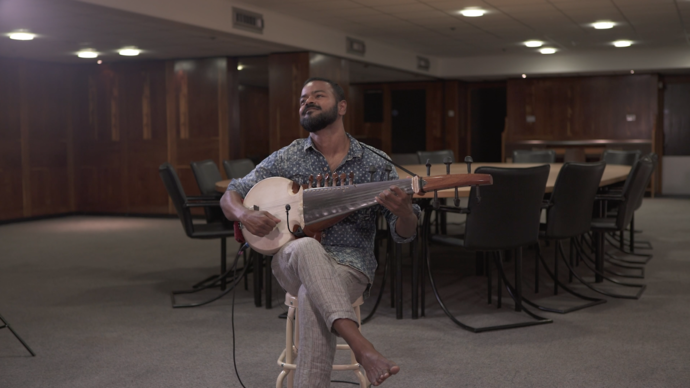 photo of man playing sarod in an empty conference room