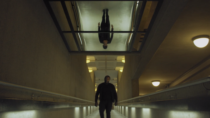 man walking down an hallway with mirror on ceiling