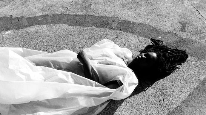 Moor Mother lying on a concrete floor