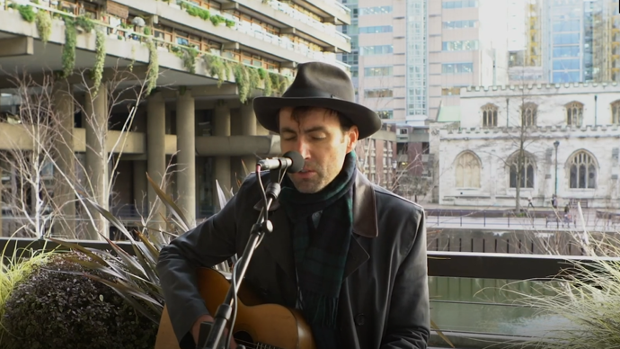 photo of andrew bird with a black hat by the barbican lakeside