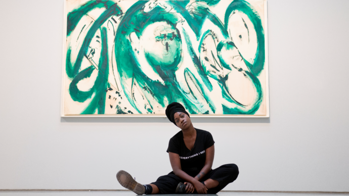 image of young poet anita barton-williams sitting on the floor in front of a green painting by lee krasner