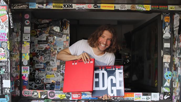 Photo of a man smiling at the camera whilst holding a record