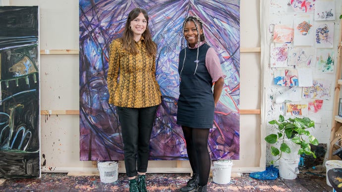Two women standing in front of a purple painting