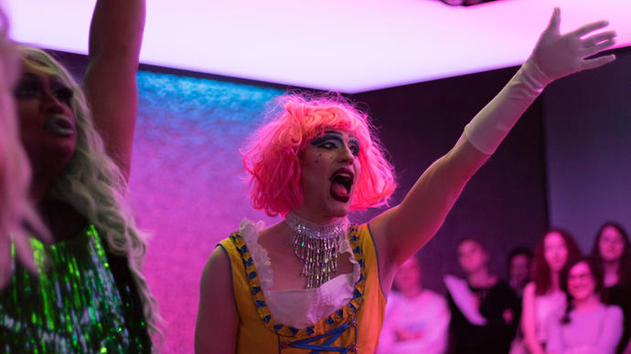 A Drag Queen with a pink wig singing