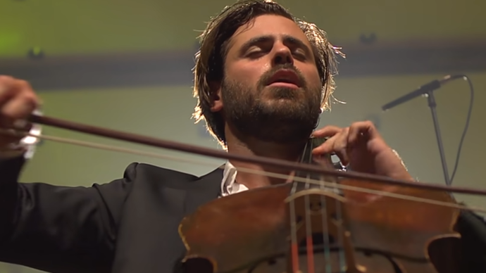 A low angle shot looking up at Hauser playing the cello