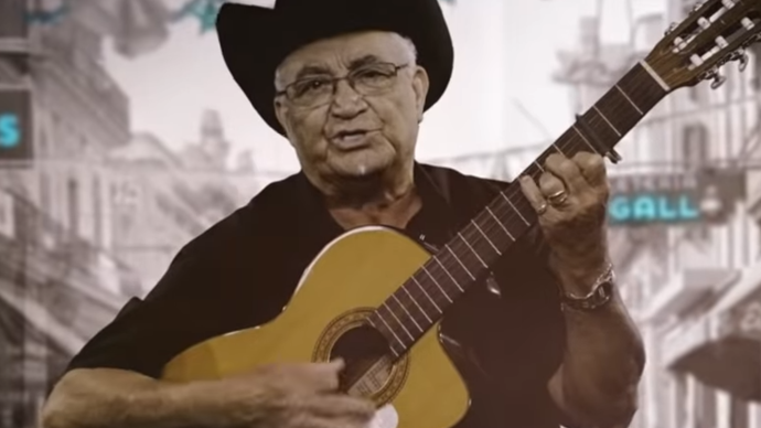 Photo of Eliades Ochoa playing the guitar towards the camera
