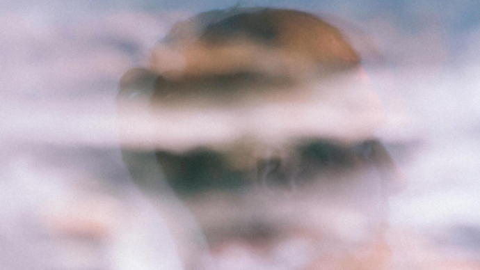 Photo of a man's reflection in a window as he is looking to the side 