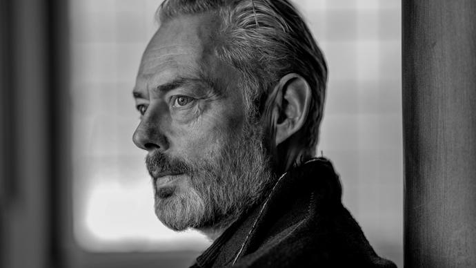 A black and white portrait of Mark Padmore gazing into the distance 