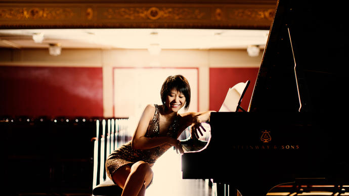 An playful image of Yuja sitting at her piano, facing the camera 