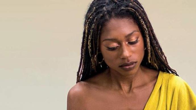 Photo of Isata Kanneh-Mason in a yellow dress playing a piano