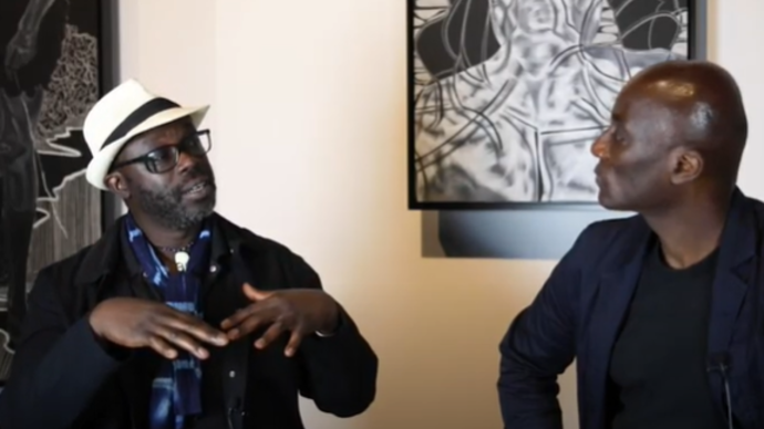 Photo of two men sitting down talking to each other