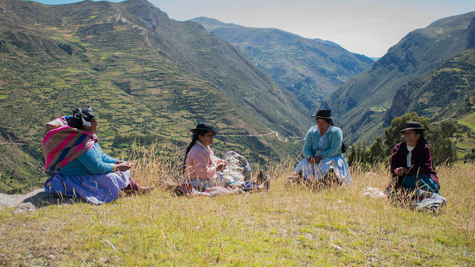 a group of women sit together up in the Peruvian mountains