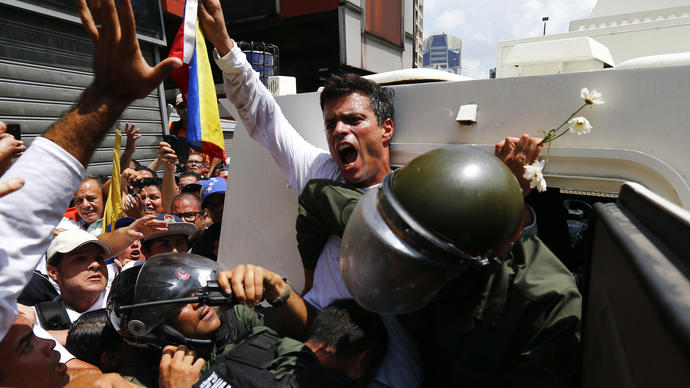 a man is pulled into a police van holding up a flag