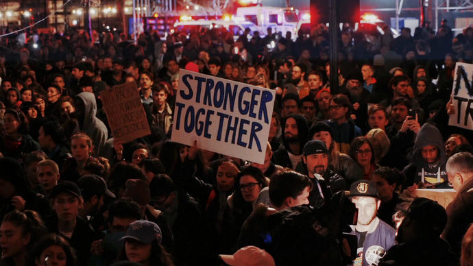 a crowd of protesters hold up signs