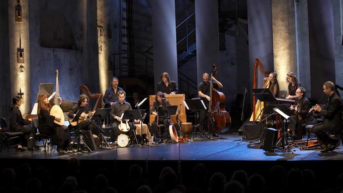 L'Arpeggiata on a lit stage, playing their period instruments