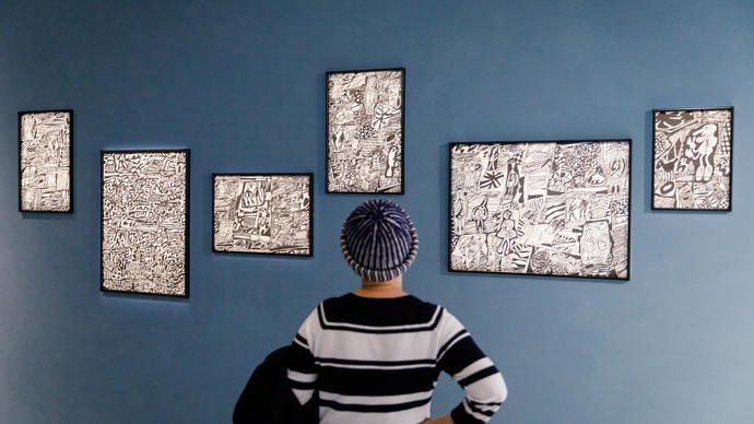 a person with a little beanie looks on Dubuffet's black and white drawings