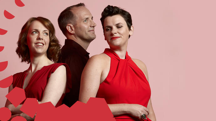 Three choir members smiling in front of a pink background