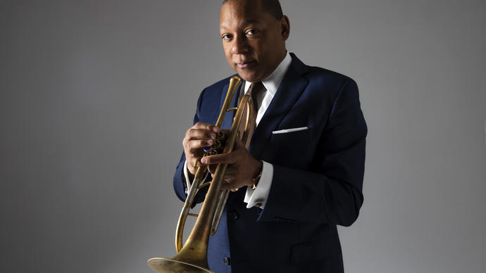 photo of Wynton marsalis against a grey background, wearing a suit and playing saxophone