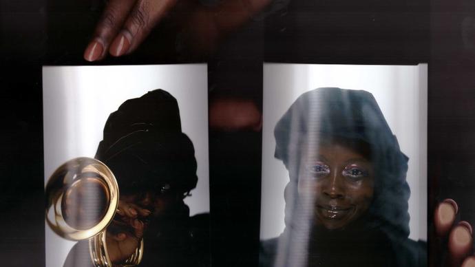 a close up photo of Klein holding up two passport sized photos of herself