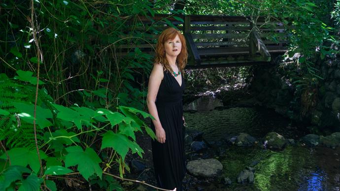 Sarah Cahill standing in a garden in front of a bridge