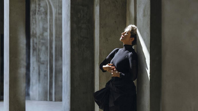Joyce DiDonato leaning against a building with her eyes closed