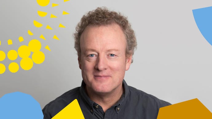 Howard Goodall smiling on a white background, with colourful shapes around the edge of the photo (BBC brainding)