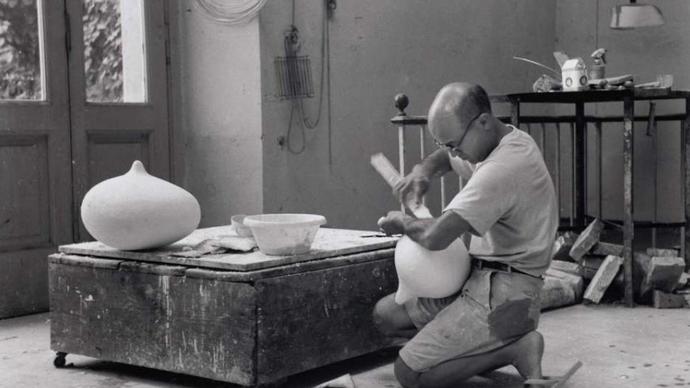 An image of Noguchi carving in his studio 