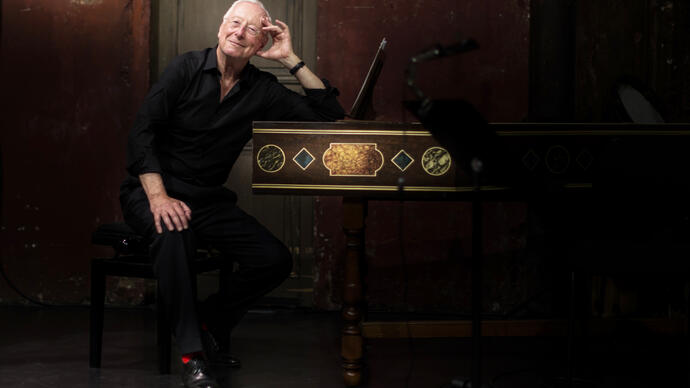 William Christie sitting at a harpsichord smiling