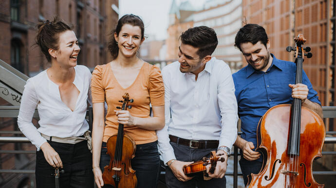 The Aris Quartett standing on a bridge holding their instruments