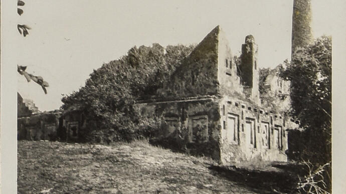 black and white picture of a building sat on a hill.