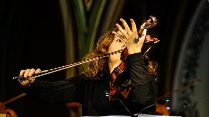 Patricia Kopatchinskaja plays her violin - it's held in front of the right hand side of her face 