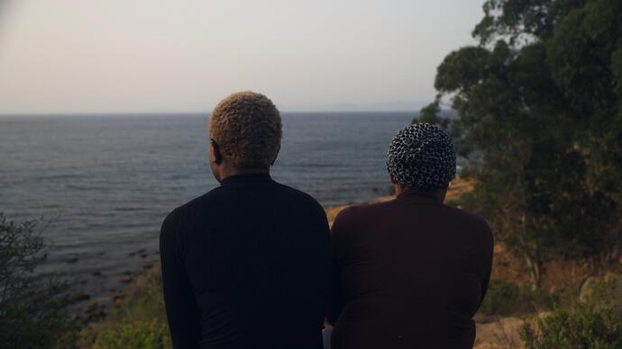 Two women sit looking into the distance