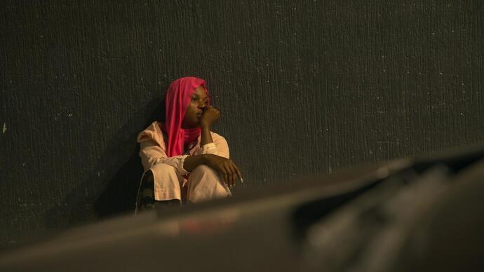 A woman sits by a car