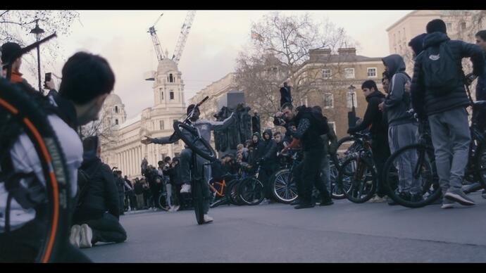 A boy performs a trick on a bike in front of a crowd