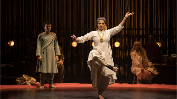 A performer dances on stage while others watch.