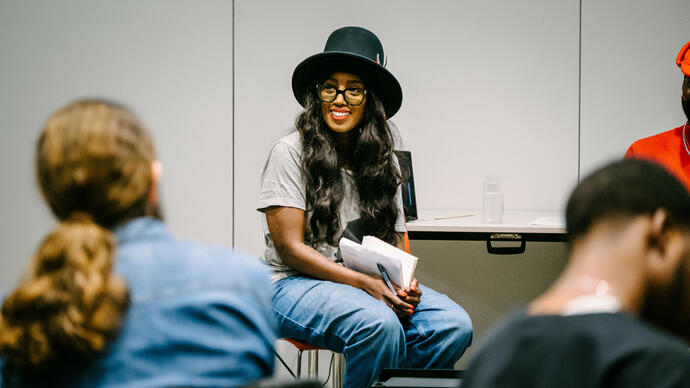 Panel host Dawn Estefan sitting in front of a white wall speaking to the audience