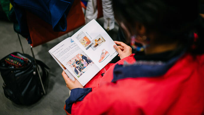 Over the shoulder view of a pamphlet on a person's lap 