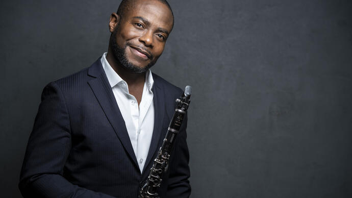 Anthony McGill smiling at the camera while holding his clarinet